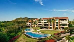 Ein Resort mit Schwimmbad, mehreren Balkonen und üppiger Bepflanzung.