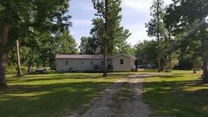 A single-story mobile home with a metal roof, surrounded by trees and a grassy yard. - Close to Wheeler's Point Boat Launch! (Baudette)