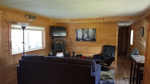 A cozy living room with a sofa, a TV, a painting, and a wooden wall. - Close to Wheeler's Point Boat Launch! (Baudette)