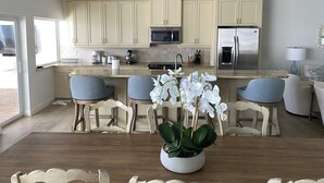 Una cucina moderna con mobili chiari, un frigorifero in acciaio inossidabile e un'area pranzo con tavolo e sedie in legno.