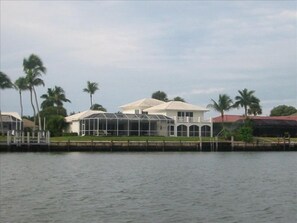 Uma propriedade à beira-mar com uma casa grande, um alpendre coberto e uma piscina.
