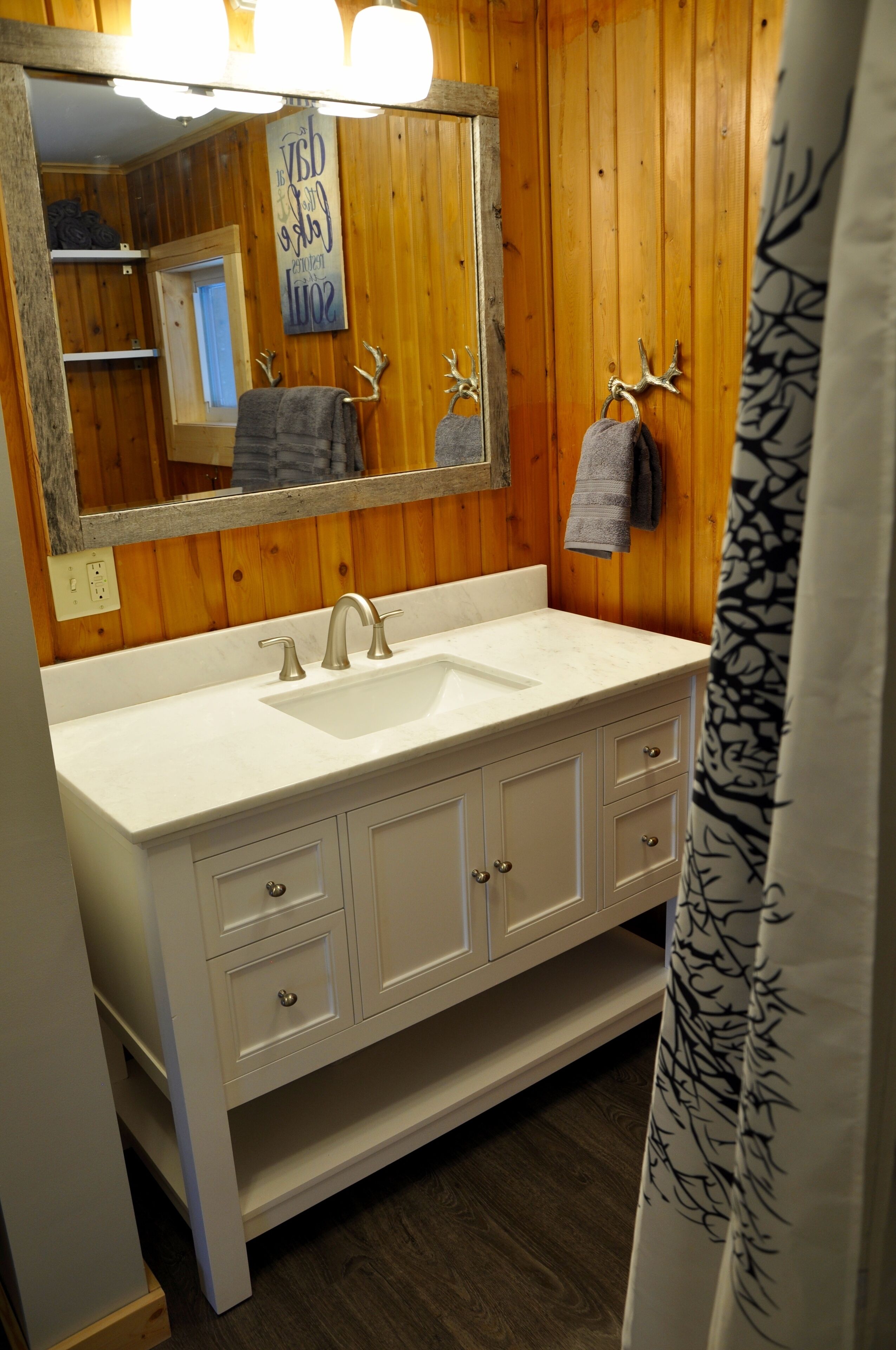 A bathroom with a wooden wall, a white sink, and a mirror.