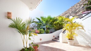 A sunlit outdoor area with a stone floor, potted plants, and a white wall with a small decorative item. - Pacific Ocean View in Pedregal- Mexican Chic 4 Bedroom Private Villa with Pool (Cabo San Lucas B.C.S)