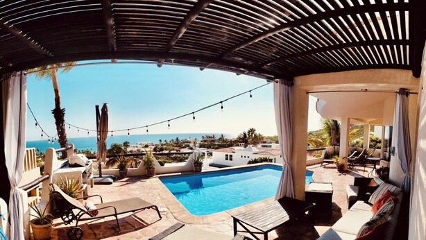 A poolside area with lounge chairs, a small pool, and a view of the ocean and buildings. - Pacific Ocean View in Pedregal- Mexican Chic 4 Bedroom Private Villa with Pool (Cabo San Lucas B.C.S)
