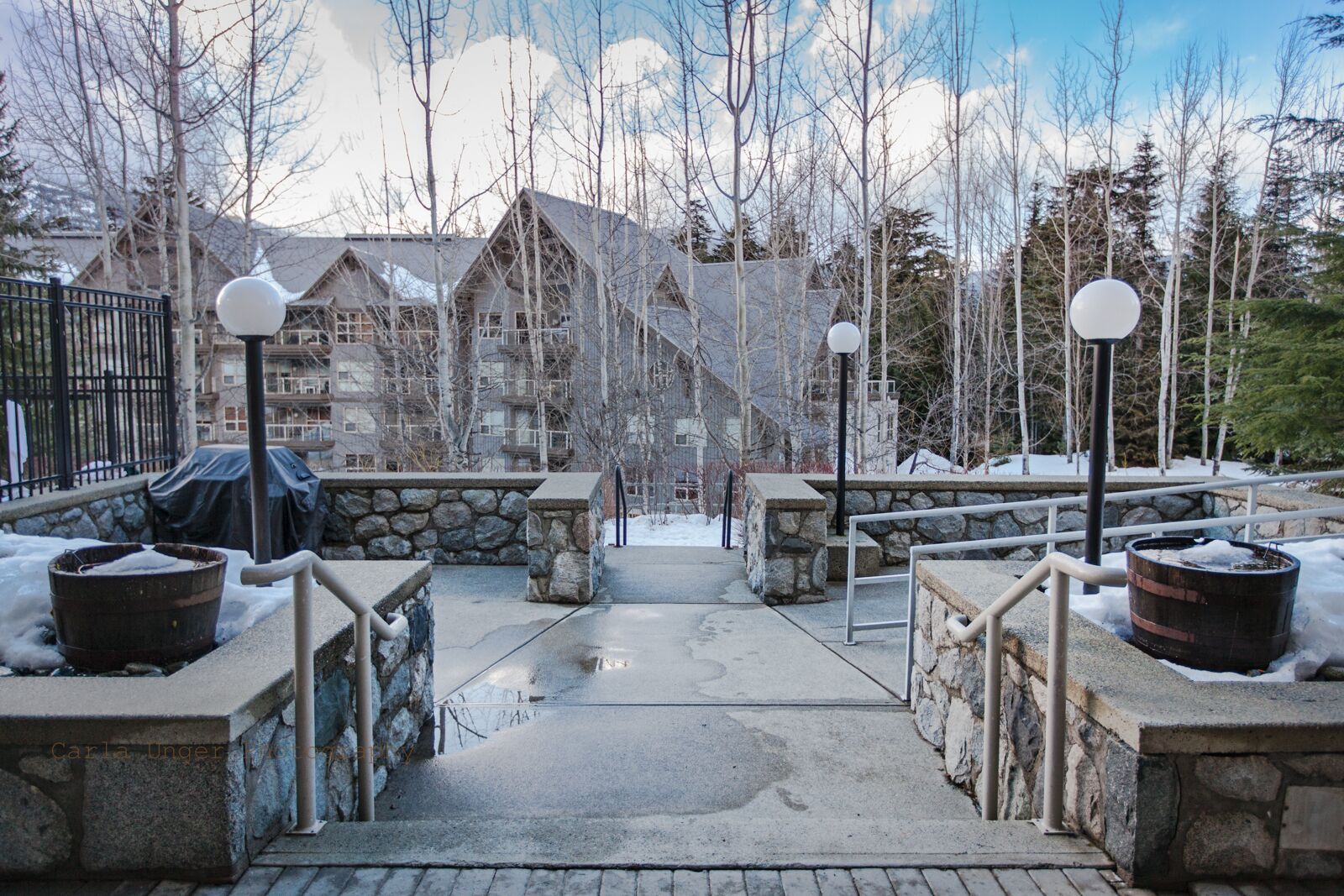 Ein verschneiter Pfad führt zu einer Lodge mit Steinschildern und Laternen.