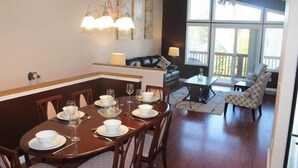 Een eetgedeelte met een houten tafel voor vier personen, een bank en een fauteuil met een patroon.
