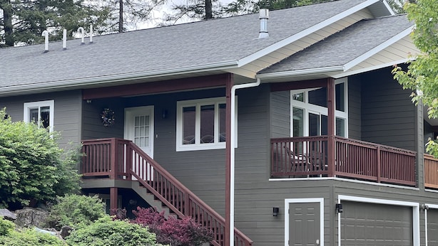 Een huis met twee verdiepingen, een overdekte veranda, een trap naar een balkon en een garage.