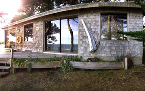 A modern house with large windows, a wooden deck, and a stone exterior.