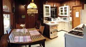 A cozy kitchen with wooden cabinets, a gas stove, and a dining area with a table and chairs.