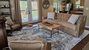 Een woonkamer met een bank, fauteuil, salontafel en een boekenkast.