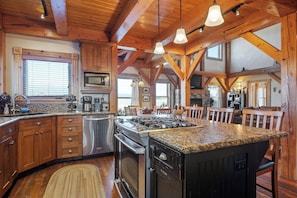 Una cocina amplia con vigas de madera, encimeras de granito y electrodomésticos de acero inoxidable, además de una isla grande.