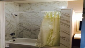 A bathroom with a shower, a bathtub, and a marble-patterned wall. - SPACIOUS AND OPEN PROPERTY W/KITCHEN - 3 MINUTES TO SUBWAY (New York)