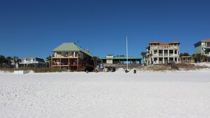 A beachfront property with multiple buildings, including a large house with a green roof and a smaller structure with a red roof. - BEACH COTTAGE 3BR , GOLF CART W/HOUSE, PORCH SWING ,POOL 30 STEPS AWAY, PETS LOV (Destin)