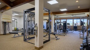 Ein Fitnessstudio mit verschiedenen Trainingsgeräten, darunter Laufbänder, Kraftgeräte und Kurzhanteln.