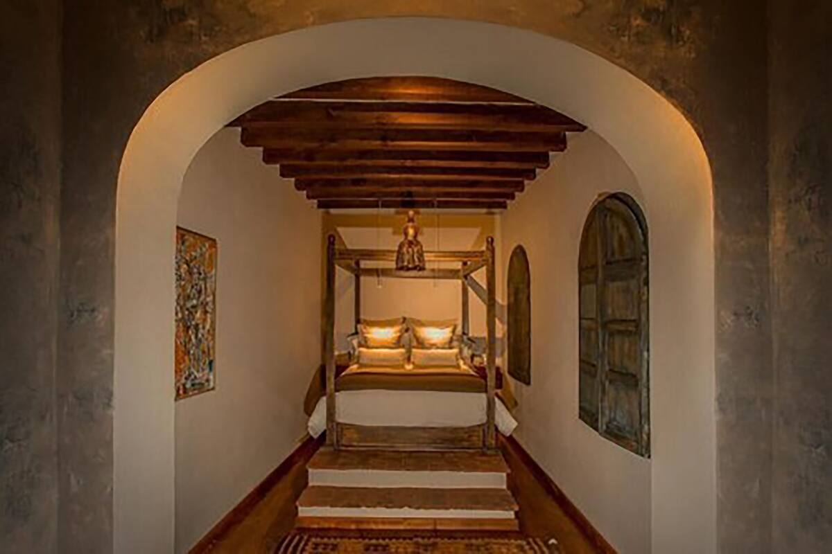 A narrow hallway with a wooden staircase leading to a bed with a canopy.