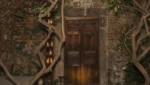 Une porte en bois rustique, adossée à un mur de pierres et ornée de lierre.