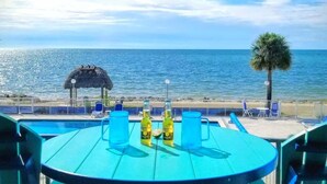 A poolside view with a table, chairs, and two bottles of Corona beer. - Oceanfront oasis beach views heated pool U34 (Marathon)
