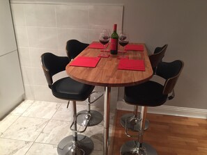 A dining table with four chairs, a bottle of wine, and wine glasses.