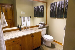 A bathroom with a wooden vanity, a sink, a toilet, and two framed pictures on the wall. - Spacious & Quiet Townhome Ideal Year-Round Location, Private Entrance (Whistler)