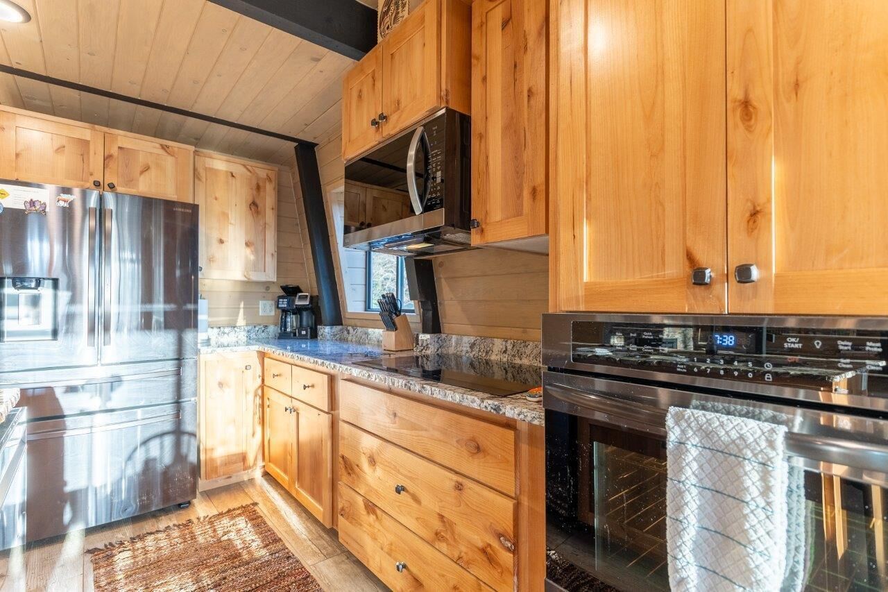 Een moderne keuken met houten kastjes, roestvrijstalen apparatuur en een granieten aanrecht.