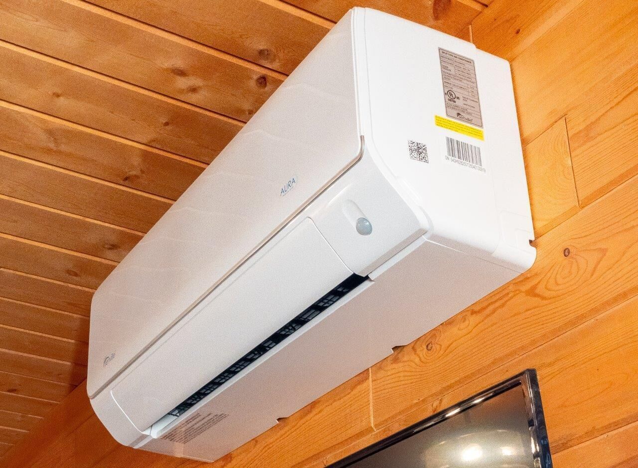 A white air conditioning unit mounted on a wooden wall.