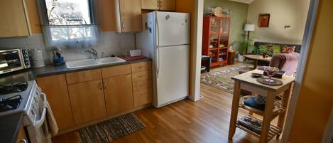 A kitchen with wooden cabinets, a refrigerator, a sink, and a window. There is a dining area with a table and chairs.