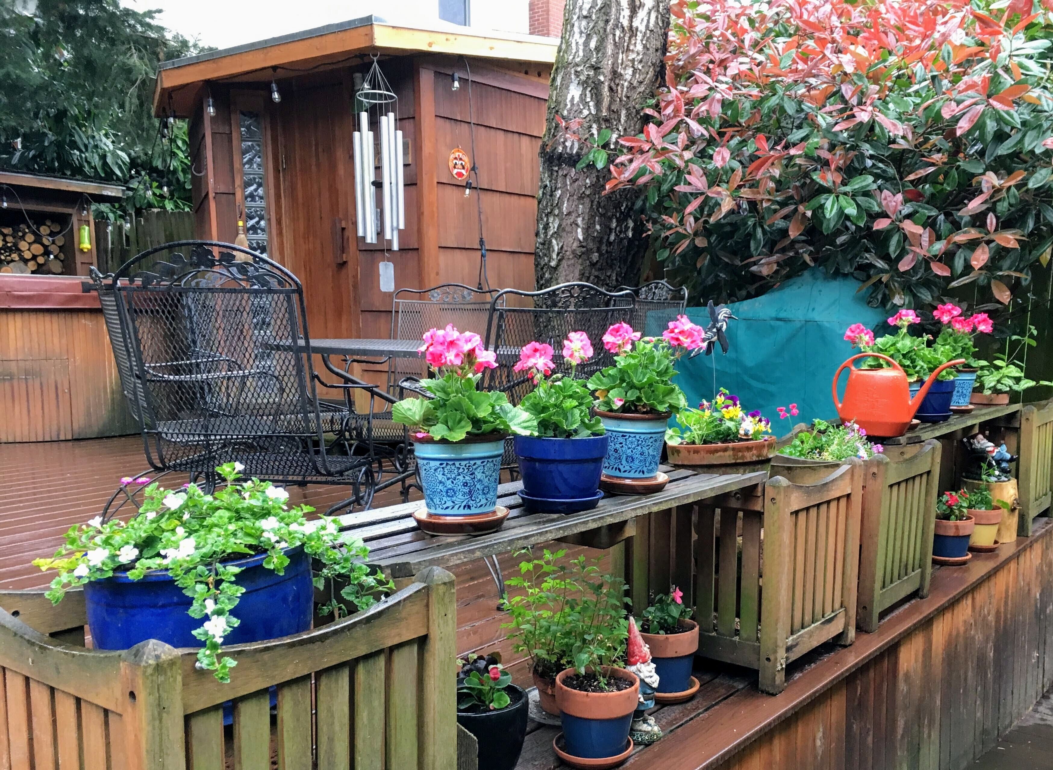 A wooden deck with metal chairs and potted plants.