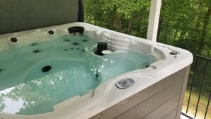 A hot tub with multiple jets, a control panel, and a view of a forested area. - Peaceful Country Cottage with Game Room & Hot Tub (Beattyville)