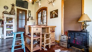 A rustic interior with a wooden desk, a TV mounted on the wall, and antlers on the ceiling.