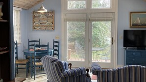 Un salón amplio con techo alto, una zona de comedor con sillas azules y un ventanal con vistas al exterior.