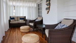 Une pièce chaleureuse avec un canapé, deux fauteuils et des poufs en osier.
