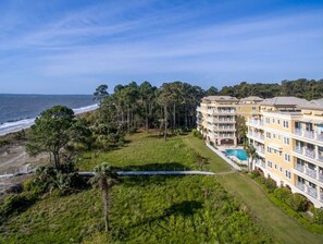 Un hotel frente a la playa con varios balcones, una piscina y vista al océano.