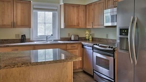A kitchen with wooden cabinets, a stainless steel refrigerator, a microwave, and a dishwasher.