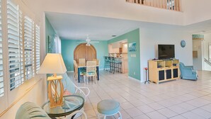 Een ruime woonkamer met een eettafel, stoelen, een televisie en een keuken op de achtergrond.