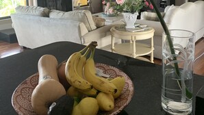 A living room with a dining table, a sofa, a television, and a decorative plant.