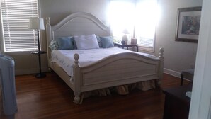 A bedroom with a bed, bedside table, lamp, and a framed picture on the wall.