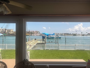 A view from a room with a large window overlooking a marina with boats, a grassy deck, and a cityscape in the background. - Fabulous Waterfront  Home. CLEARWATER BEACH. Bayfront. Large private dock (Clearwater Beach)