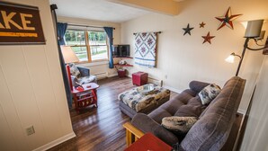 Una sala de estar acogedora con un sofá, una mesa roja y un televisor.