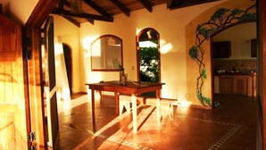 A room with a wooden table, two mirrors, a tiled floor, and a view of a kitchen through an archway. - Jungle Retreat a House on the beach in the middle of the jungle (Rincon)