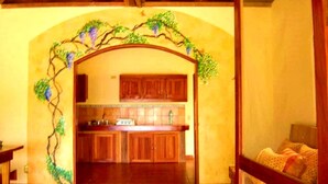 A kitchen with wooden cabinets, a countertop, and a hanging vine decoration. - Jungle Retreat a House on the beach in the middle of the jungle (Rincon)
