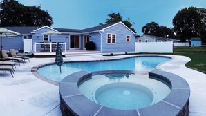 En baghave med swimmingpool, liggestole og en overdækket terrasse.