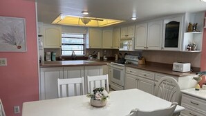 A kitchen with white cabinets, a dining table with chairs, and a central island with a flower arrangement.