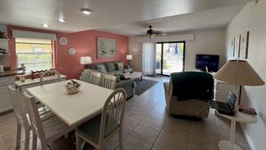 A spacious living area with a dining table, chairs, a sofa, and a TV.