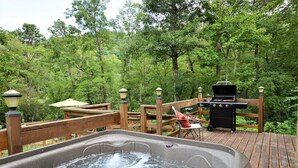 A hot tub on a wooden deck surrounded by lush greenery. - Beautiful, pet friendly secluded cabin with fire place and hot tub. (Robbinsville)