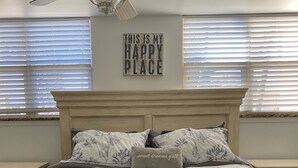 Une chambre à coucher avec un lit, un ventilateur de plafond et un panneau accroché au mur.