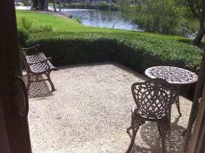 Relax on the patio with a view of the serene grassy area and tranquil body of water.