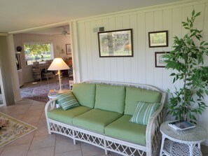 Relax in this inviting living room with a comfortable sofa, framed artwork, and a potted plant.