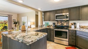 A modern kitchen with granite countertops, stainless steel appliances, and dark wooden cabinets. - Newly Remodeled Ocean View Condo, 2 bedroom, 2 bath, No stairs!  (Princeville)