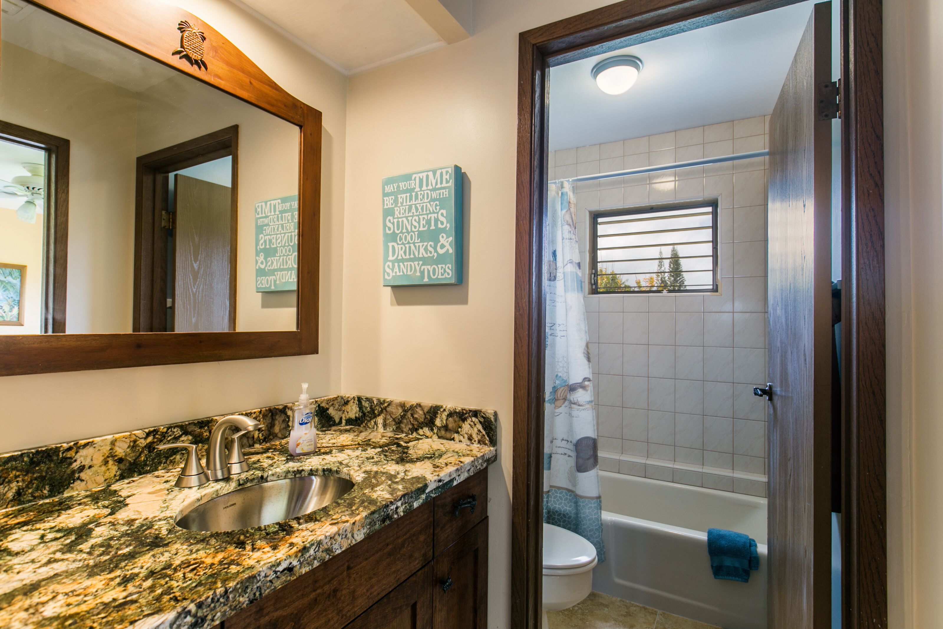 Une salle de bain avec un lavabo doté d’un plan de travail en granit, un miroir, un porte-serviettes et un rideau de douche.