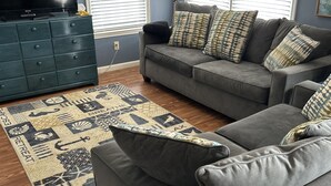 A living room with a grey sofa, a dark blue wall, and a patterned rug.